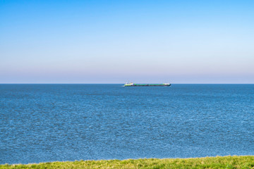 Seascape with blue sea and a large ship on the horizon. Coastline and sea in Oostvaardersplassen, Almere, The Netherlands.