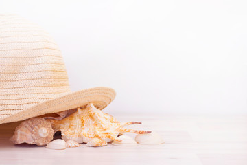 Seashells and straw hat on a wooden light background. Travel and vacation concept.