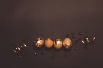 Beautiful brown and golden easter eggs on dark background , flat lay