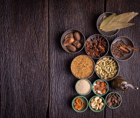 Obraz na płótnie Canvas Set of various spices on rustic wood background. Pepper, turmelic, paprika, basil, rosemary, chilly, cardamom, cinnamon, anise. Top view with copy space.