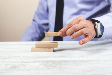 Businessman holding wooden cube on a wooden table.