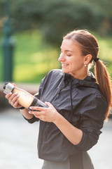 Happy sportive woman drinking water during fitness exercises