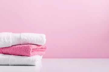 Stack of soft towels on pink background, bathroom
