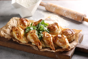 Bakery products. Pies on the board near  a rolling pin, flour on a light background. Background image, copy space