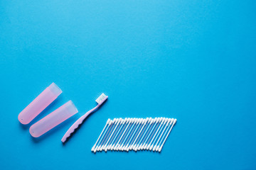  Hygiene products and daily routine. Toothbrush with bacterial protective cover, cotton swabs and toothbrush on a blue background with top view and copy space