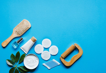 Daily hygiene products.Cotton swab,cream,lotion and environmentally friendly comb and  wooden massage roller over blue background with top  view and space for text