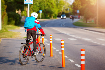 Child with rucksack riding on bike in the park near school