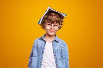 Fototapeta Curious pupil with textbook on head obraz