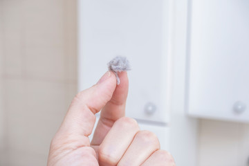 A hand holding a large piece of dust in fingers, dusty and dirty home concept