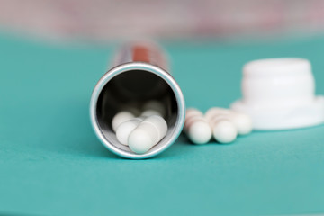 White medical capsule of medicine in a tube close-up on a blue background. Medical background with...
