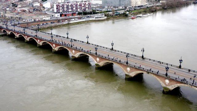 Pont de Pierre pedestrian bridge that crosses the Garonne river in Bordeaux France from the Napoleonic era, Aerial flyover left-pan reveal shot
