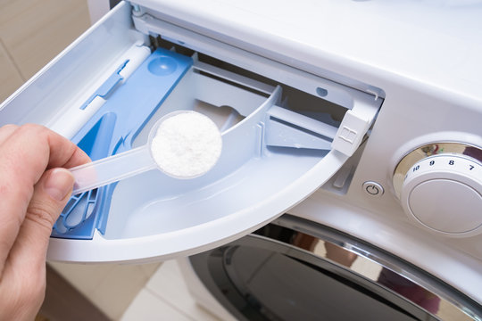 A housewife adding a phosphate-free detergent to a washing machine drawer.
