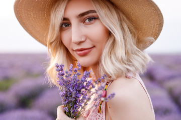 Beautiful stylish woman with lavender flowers in hand looking at camera