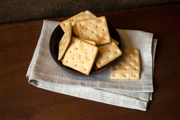 salted crackers with herbs from rice flour. Gluten free. Cookies in a clay bowl on a burlap background.