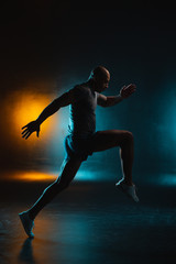 Fototapeta na wymiar Dark studio photo of sportsman in motion stock photo