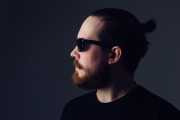 Obraz premium Handsome young man with a beard and mustache in sunglasses in fashionable clothes.