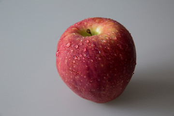  Ripe red apple on the table. There are drops of water on an apple.