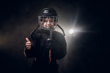 Young blonde fit boy, ice hockey player, posing in a dark studio for a photoshoot, wearing an...