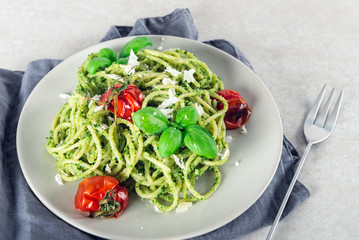 Pasta spaghetti with homemade pesto sauce, roasted tomatoes and fresh basil leaves, vegetarian food