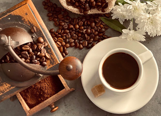cup of coffee with beans and an old coffee grinder