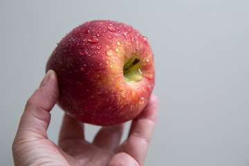 Drops of water on a red juicy apple. An apple in a female hand.