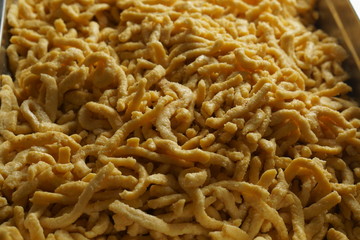 a pile of homemade swabian spaetzle pasta noodles in a castronrom pan container