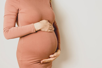 Pregnant woman with her hands on her belly, close up.