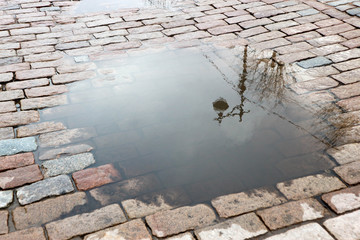 autumn mood reflection of street lantern in the puddle on stone pavement