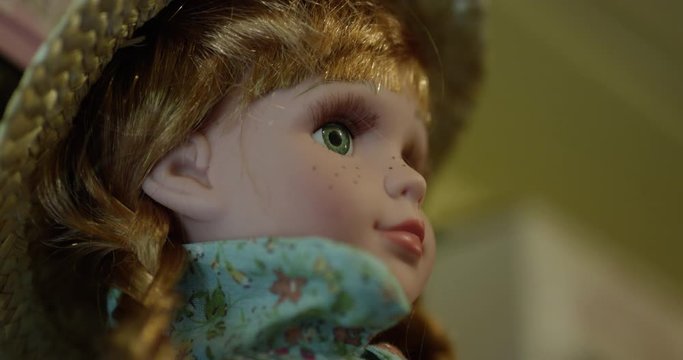 Red headed doll sitting on shelf looking out into room - close up on dolls eyes
