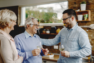 Happy man talking to his senior parents in the kitchen.