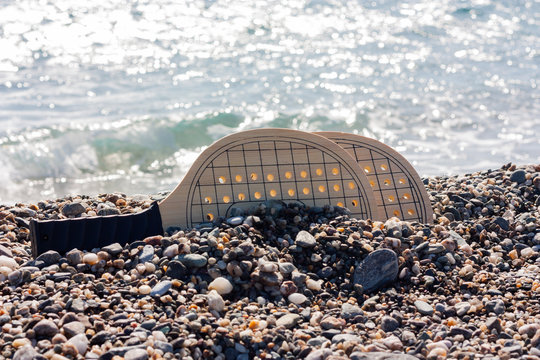 Set for game of beach tennis, wooden rackets on background di pabble beach.