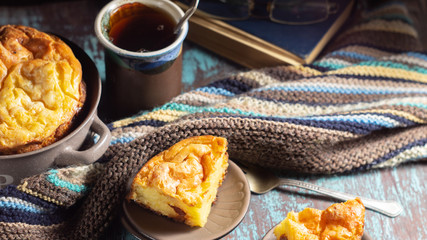 Cottage cheese casserole, cup of tea and a woolen scarf on a wooden table