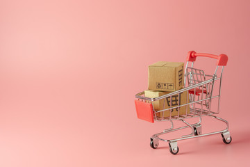 Shopping concept : Cartons or Paper boxes in red shopping cart on pink background. online shopping consumers can shop from home and delivery service. with copy space