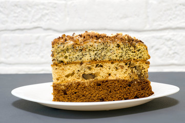 Chocolate cake with a separate piece on a white plate on a gray background