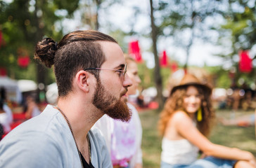 Fototapeta premium Side view of young man sitting at summer festival.