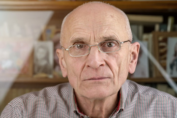 cheerful senior man in glasses by vintage bookcase at home