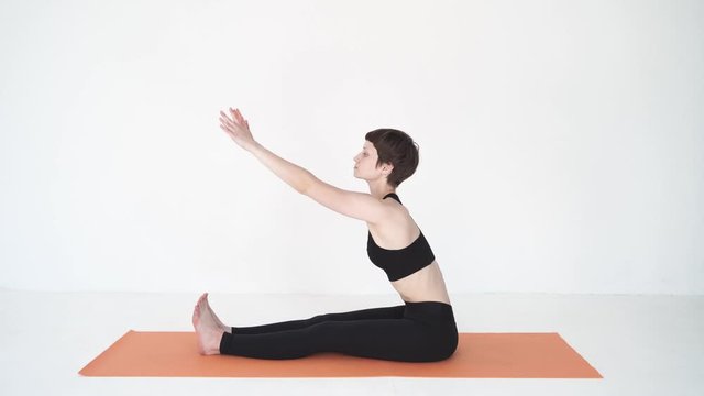Young woman practicing yoga intense bend paschimottanasana in white studio