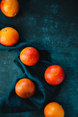 Flat lay food composition with blood oranges on a dark blue background.