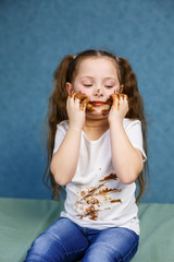 little girl eats chocolate and smudges her white t-shirt, face and hands him