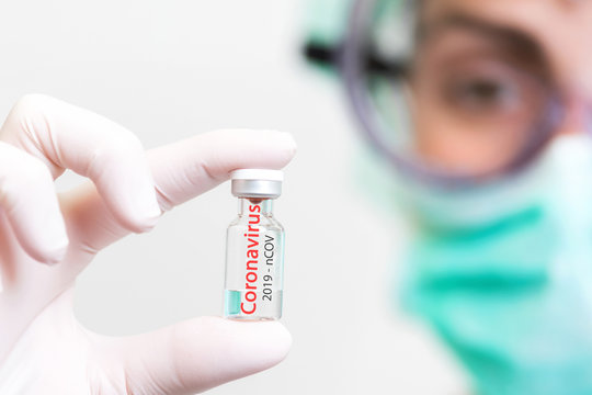 A doctor in medical gloves and mask holding an ampula with vaccine. Close up shot. Coronavirus, epidemic and medicine concept .