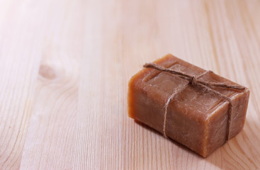 A piece of brown soap on a wooden surface. Copy space. Place for text.