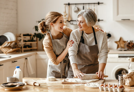 happy family grandmother  old mother mother-in-law and daughter-in-law daughter cook in kitchen, knead dough, bake cookies.