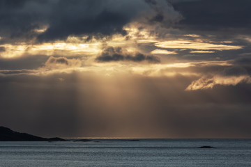 Sonnenstrahlen brechen duch dunkle Wolken über dem Atlantik vor Norwegen. - obrazy, fototapety, plakaty