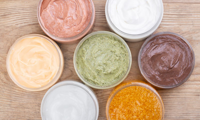 Set of cans of cream of various colors on wooden background