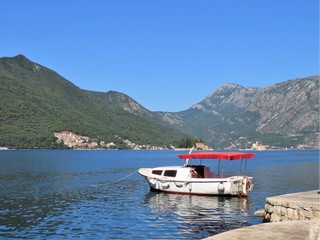 Small boat floating in the water with mountains in the background - 325847860