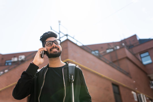 Young Indian Student Man With Backpack Talking On The Phone In The Street