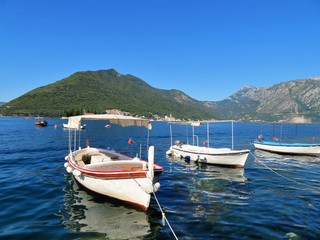 Small boats floating in the water with mountains in the background - 325848014