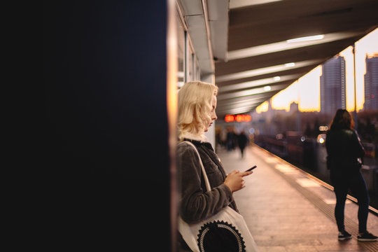 Young woman using smart phone waiting for train at subway station - Powered by Adobe