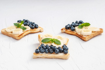Homemade sandwiches with cottage cheese, blueberries, banana, mint on a white background with copy space