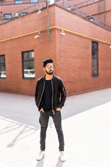 Indian handsome man in sunglasses standing in front of brick building on the street